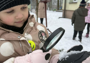 Dziewczynka obserwuje śnieg przez lupę