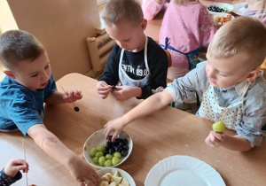 Chłopcy nadziewją kulki winogrona