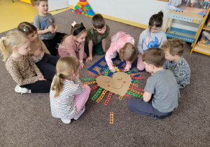 Dzieci siedzą na dywanie