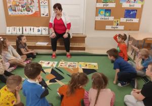 Dzieci siedza na dywanie w półkolu