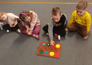 Dzieci siedzą na dywanie