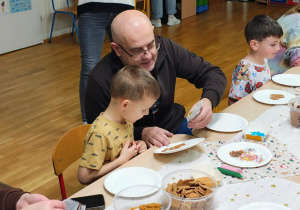 Dzieci z rodzicami dekorują pierniczki