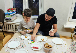 Dzieci z rodzicami dekorują pierniczki