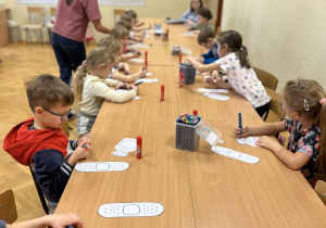 Dzieci kolorują przy stolikach