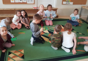 Dzieci siedzą na dywanie