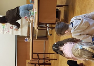 Pani wiesza rysunki na tablicy