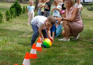 Chłopiec toczy piłkę miedzy pachołkami