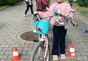 Dziewczynka stoi przy rowerze