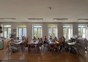 Grupa Jablcusie gotowa do warsztatów pozuje do zdjęcia przy stolikach