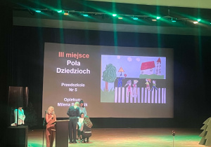 Moment wręczania nagrody na scenie podczas ogłaszania wyników konkursu plastycznego