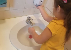 dziewczynka w żółtej bluzce myje ręce