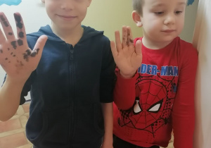 chłopcy pokazują ubrudzone dłonie